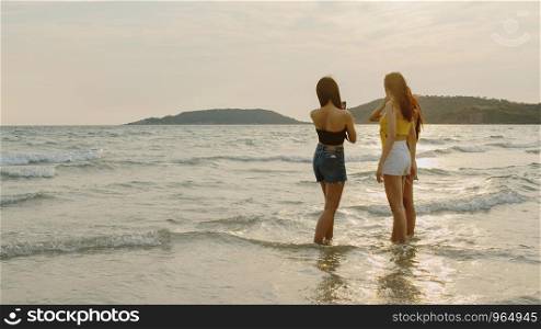 Group of Asian women talking together enjoy funny moment on beach, Beautiful female relax on beach near sea when sunset in evening. Woman travel on beach in summer concept.
