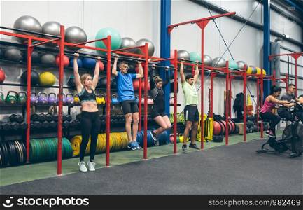 Group of athletes doing pull ups in the gym. Athletes doing pull ups in the gym