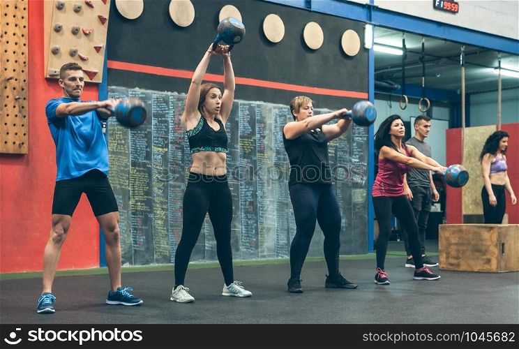 Group of athletes exercising with kettlebells indoors. Athletes exercising with kettlebells indoors