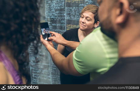 Group of athletes looking at the mobile of a gym mate. Selective focus on woman in background.. Athletes looking at the mobile of a gym mate