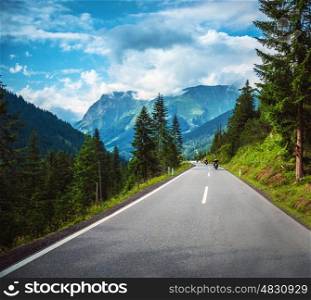 Group of bikers riding on road pass along Alpine mountains, travelers in Europe, mountainous highway, pine tree forest, extreme sport concept