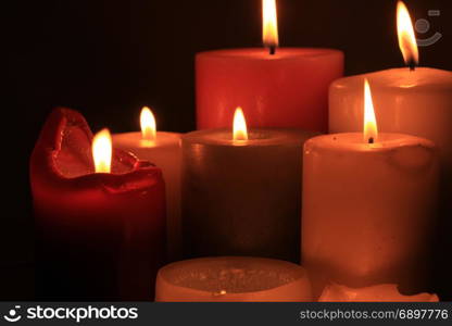 Group of burning candles in different heights and colors