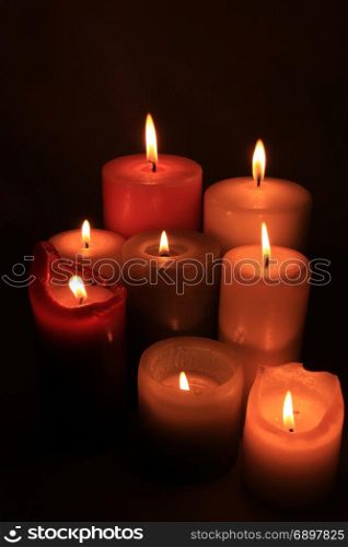 Group of burning candles in different heights and colors
