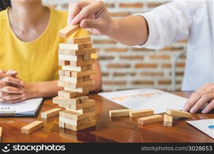 Group of business creative people building tower by wooden blocks, doing a plan for brainstrom business strategy, risk, future, teamwork concept. Group of business creative people building tower by wooden block