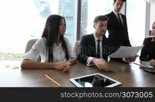 Group of business partners discussing reports and planning work in office