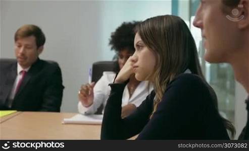 Group of business people during meeting in corporate conference room. A woman gets a headache and touches her temples. Medium shot