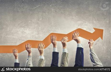 Group of business people holding growing graph in raised hands