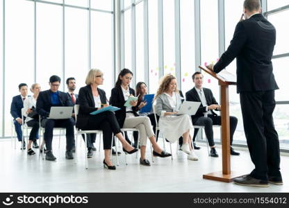 Group of business people meeting in a seminar conference . Audience listening to instructor in employee education training session . Office worker community summit forum with expert speaker .