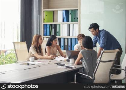 Group of business people meeting in conference room. Asian businessman speech, present teamwork partnership. Happy business people meeting present graph chart investment, business data in meeting room
