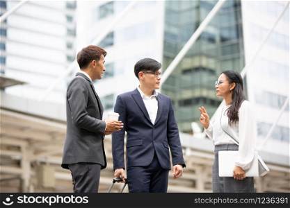 Group of business people standing with hand shaking on business agreement or teamwork against building