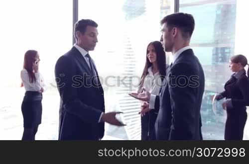 Group of business people talking in office, skyscrapers on background