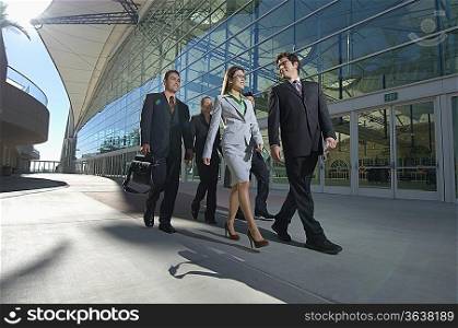 Group of business people walking past office building