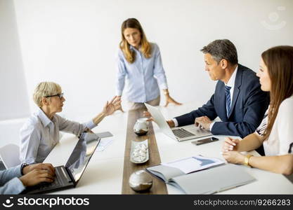 Group of business people with young adults and senior woman colleague on meeting at the modern bright office interior