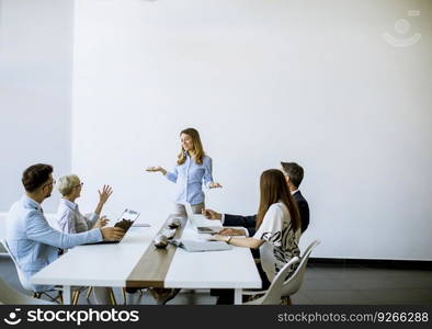 Group of business people with young adults and senior woman colleague on meeting at the modern bright office interior