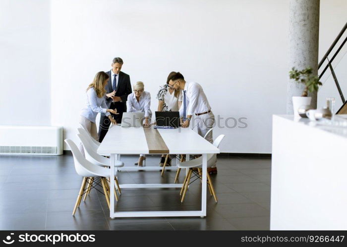 Group of business people with young adults and senior woman colleague on meeting at the modern bright office interior