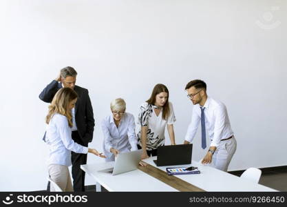 Group of business people with young adults and senior woman colleague on meeting at the modern bright office interior