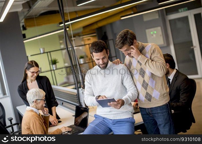 Group of business people working and communicating while standing in  the office together with colleagues sitting in the background