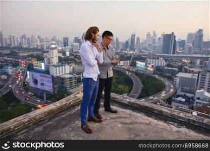 Group of business people working on a rooftop with blurry city b. Group of business people working on a rooftop with blurry city background, business technology concept. Group of business people working on a rooftop with blurry city background, business technology concept