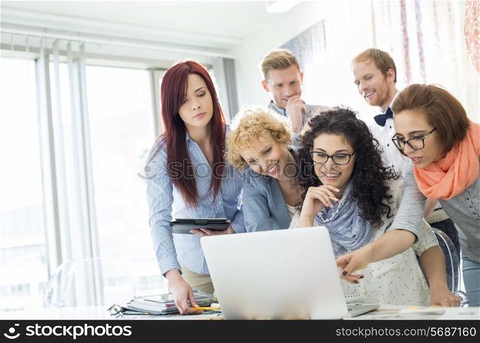 Group of businesspeople using laptop at desk in creative office