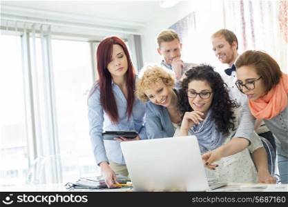 Group of businesspeople using laptop at desk in creative office