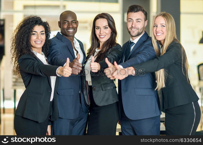 Group of businesspeople with thumbs up gesture in modern office. Multi-ethnic people working together. Teamwork concept.