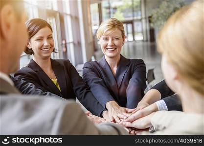 Group of businesswomen and men in a circle with hands together