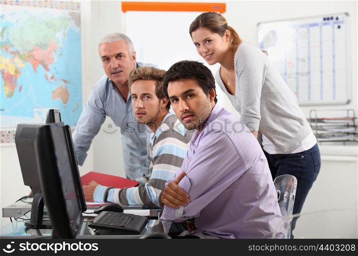 Group of casually dressed people working round a computer