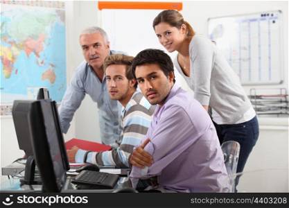 Group of casually dressed people working round a computer