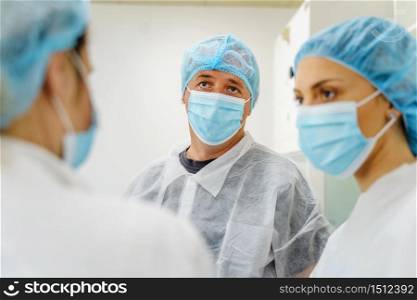 Group of caucasian doctors or scientists at hospital or laboratory - Man and woman people wearing protective equipment mask and bouffant cap talking - protection and solution concept