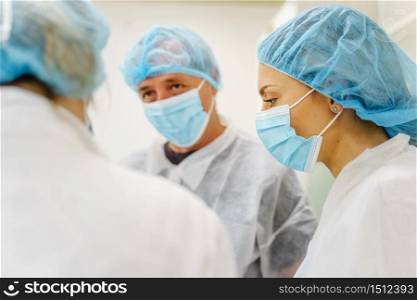Group of caucasian doctors or scientists at hospital or laboratory - Man and woman people wearing protective equipment mask and bouffant cap talking - protection and solution concept
