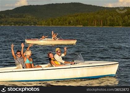 Group of cheerful friends racing with motorboats on river