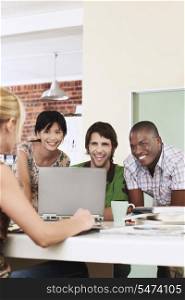 Group of cheerful multiethnic business people using laptop in meeting room