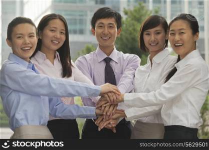 Group of cheerful young business people with hands on top of each other