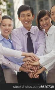 Group of cheerful young business people with hands on top of each other