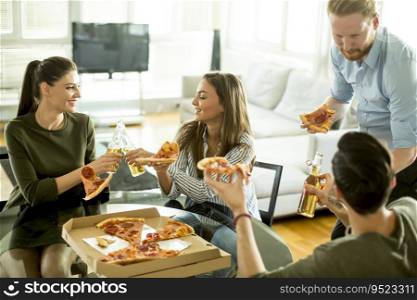 Group of cheerful young people eating pizza in the room and having fun