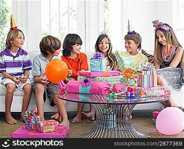 Group of children (7-12) sitting on sofa at birthday party