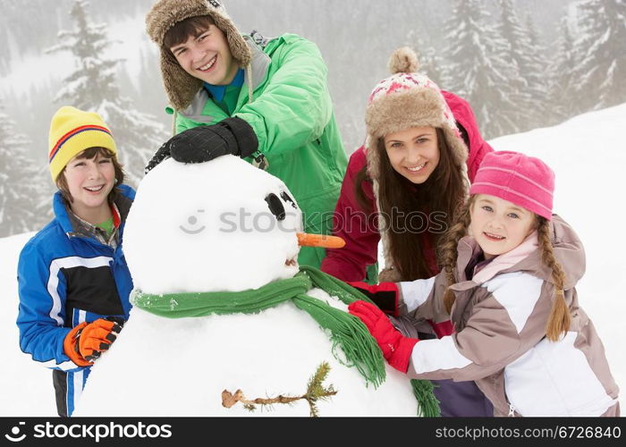 Group Of Children Building Snowman On Ski Holiday In Mountains