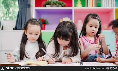Group of children drawing in classroom, Multi-ethnic young boys and girls happy funny study and play painting on paper at elementary school. Kids drawing and painting at school concept.