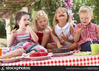 Group Of Children Eating Jelly And Cake At Outdoor Tea Party