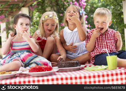 Group Of Children Eating Jelly And Cake At Outdoor Tea Party