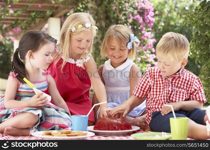 Group Of Children Eating Jelly At Outdoor Tea Party