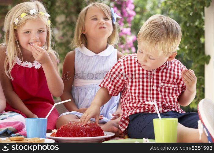 Group Of Children Eating Jelly At Outdoor Tea Party