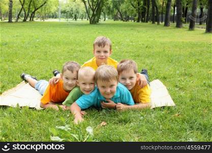 Group of children lying on the grass in the summer park