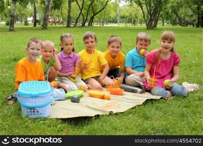 Group of children sitting together on teh grass in the park