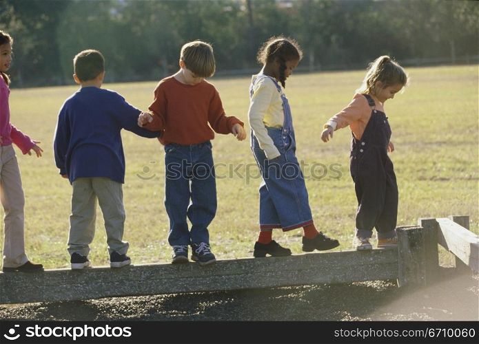 Group of children walking on a wooden log