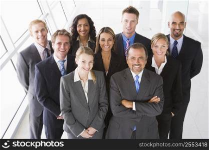 Group of co-workers standing in office space smiling (high key)