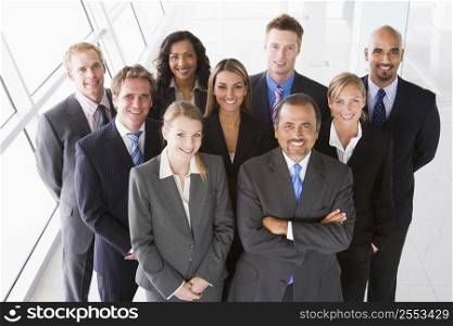 Group of co-workers standing in office space smiling (high key)