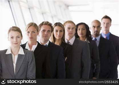 Group of co-workers standing in office space smiling (high key/depth of field)
