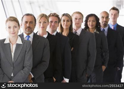 Group of co-workers standing in office space smiling (high key/depth of field)