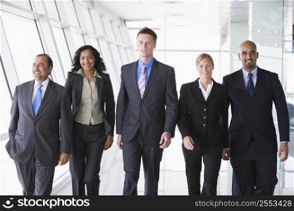 Group of co-workers walking in office space smiling (high key)
